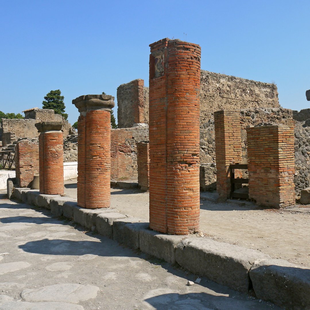 Tall brick columns lining a paved Roman street in the Pompeii ruins