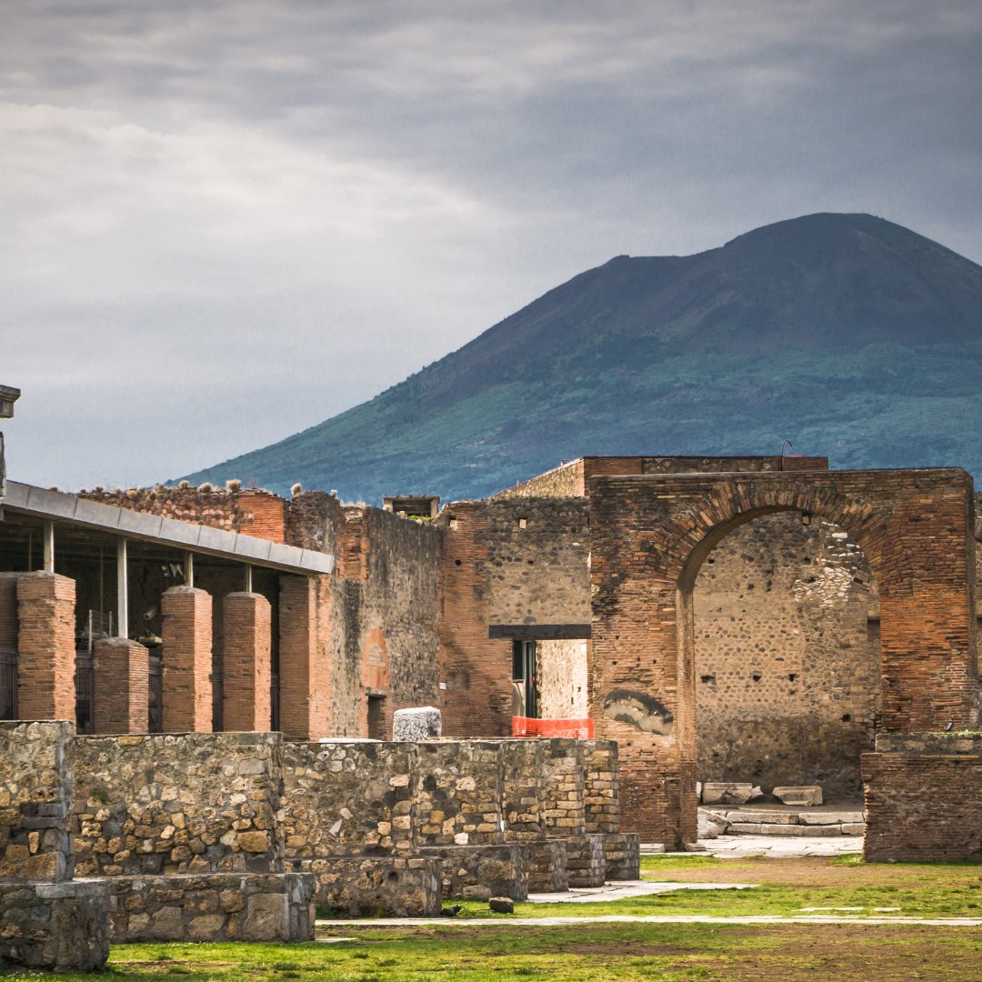 The Forum of Pompeii at sunset with the dome of Mount Vesuvius behind it