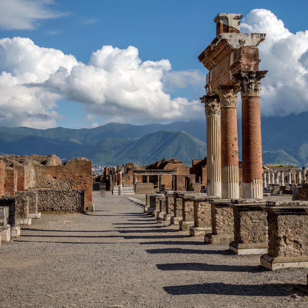 The Pompeii Forum colonnade with surviving Corinthian columns under a cloudy sky